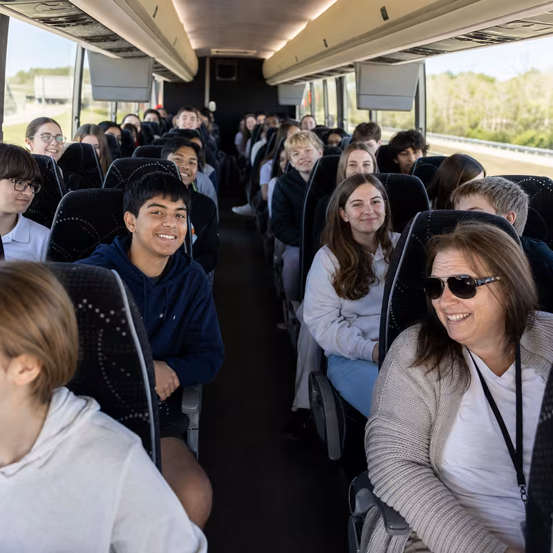 Group boarding a white charter bus for School Transportation transportation in Brooklyn